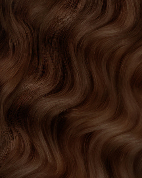 A swatch of Maryann medium ash brown curly hair extensions, showcasing rich texture and color.