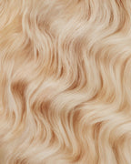 A swatch of wavy ash blonde hair extensions, showcasing soft waves and a natural sheen.