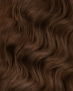 A swatch of wavy medium ash brown hair extensions, showcasing rich texture and color.