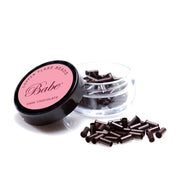 A jar of dark chocolate Babe beads, with copper flare beads scattered in front of the jar.